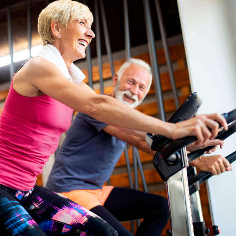 Seniorin und Senior auf Trimmrad (Fahrrad) beim Sport