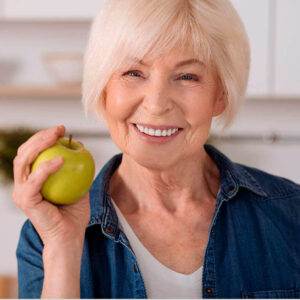 Lächelnde Seniorin hält Apfel in der Hand