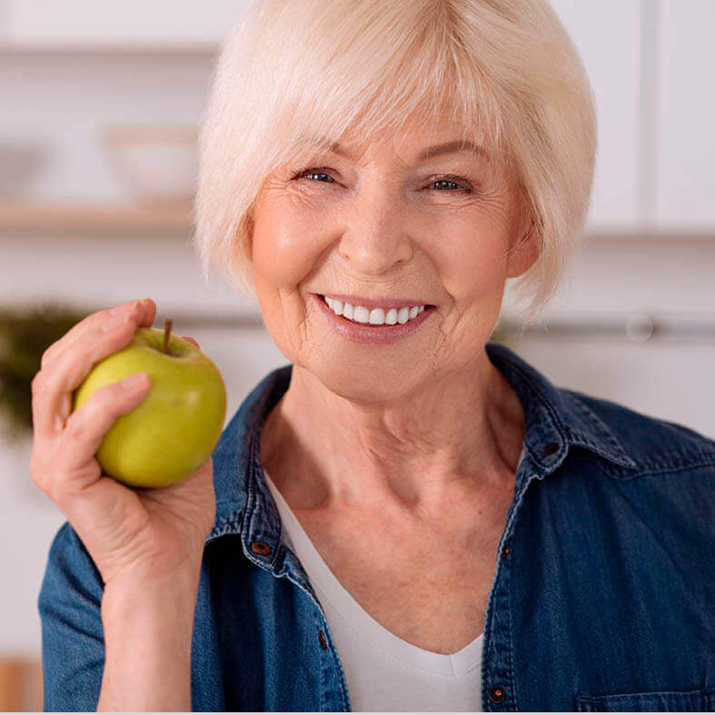 Lächelnde Seniorin hält Apfel in der Hand