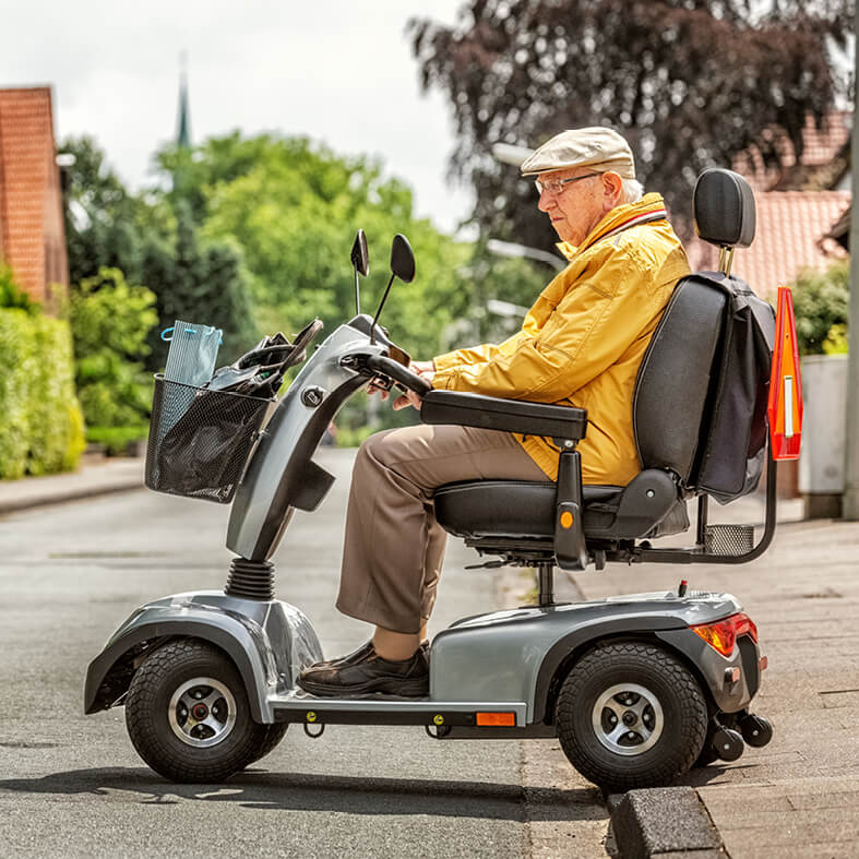 Senior fährt mit Elektrodreirad über die Straße | Senioren im Straßenverkehr