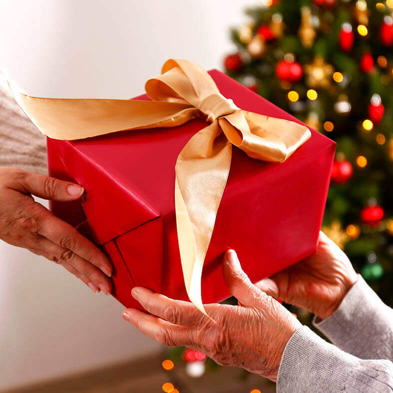 Geschenke für Senioren: Mutter überreicht Weihnachtsgeschenk an ihre Mutter