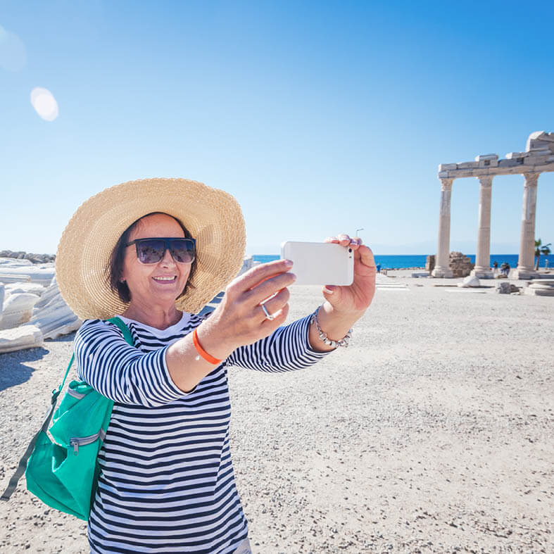 Seniorin macht Selife mit Smartphone im Urlaub am Strand