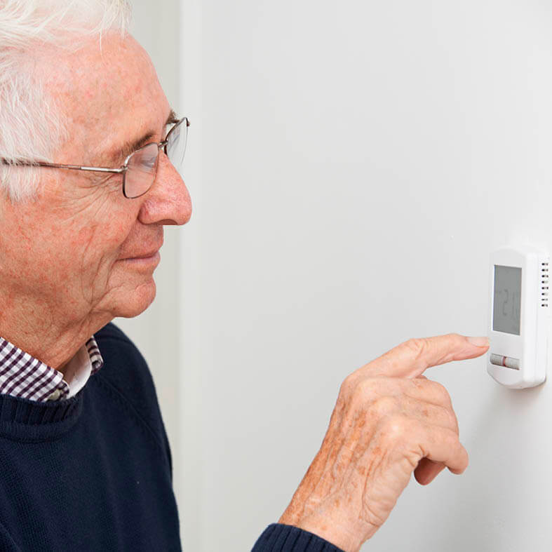 Senior senkt Thermostat der Heizung